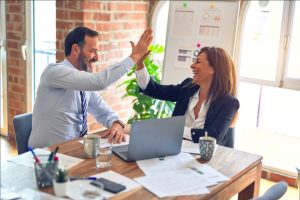 A pair of sales executive high-fiving in a meeting room