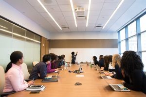 Group of employees sitting in a conference room attending a weekly meeting